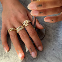 Hand wearing multiple gold rings on a textured surface - seolgold