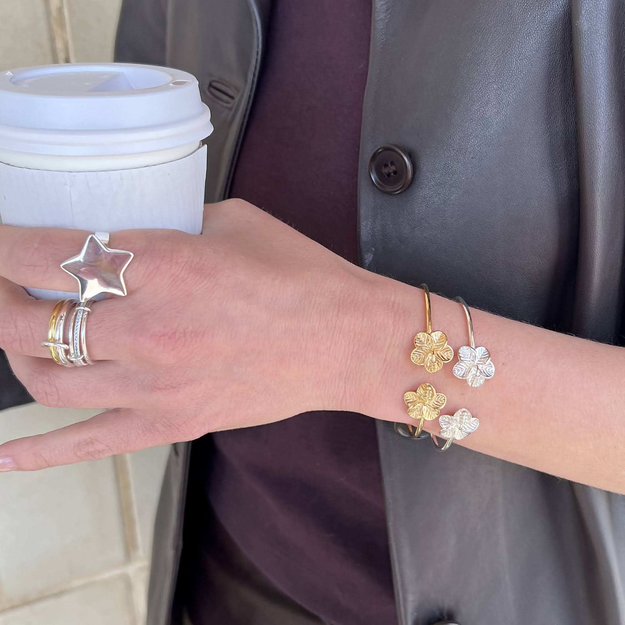 Hand wearing gold and silver rings and bracelets holding a coffee cup - seolgold