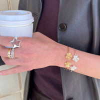 Hand wearing gold and silver rings and bracelets holding a coffee cup - seolgold