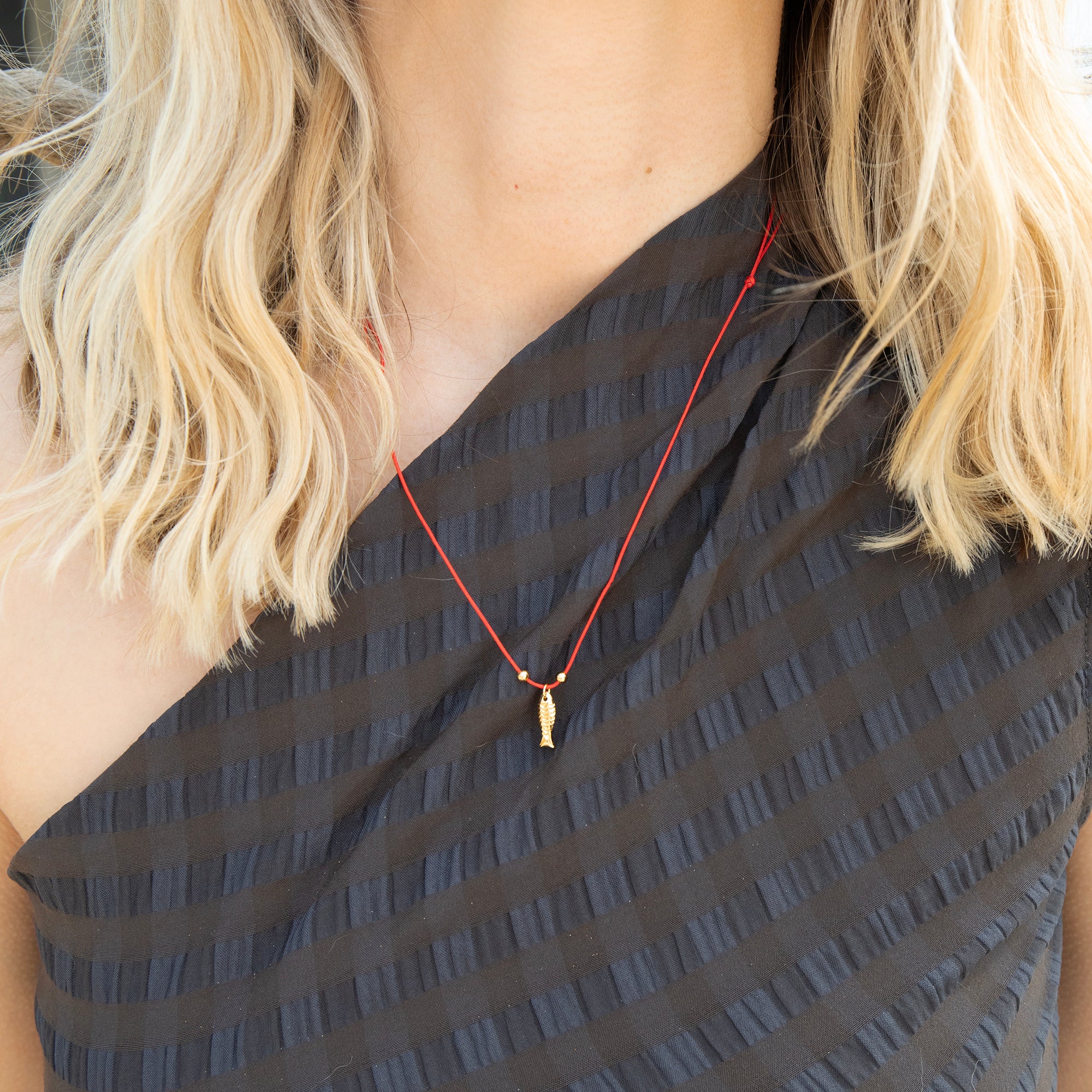 Person wearing a black top with a red fish necklace and blonde hair - seolgold