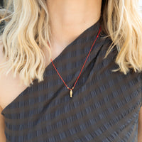 Person wearing a black top with a red fish necklace and blonde hair - seolgold