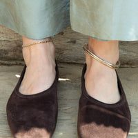 Brown suede shoes worn with light-colored pants on a wooden floor - seolgold