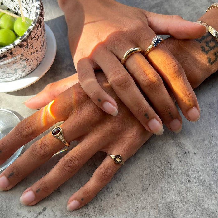 Two hands with gold rings on a concrete surface - gold signet ring 