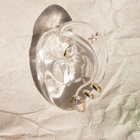 Clear acrylic earring display stand with jewelry on a textured beige surface - seolgold