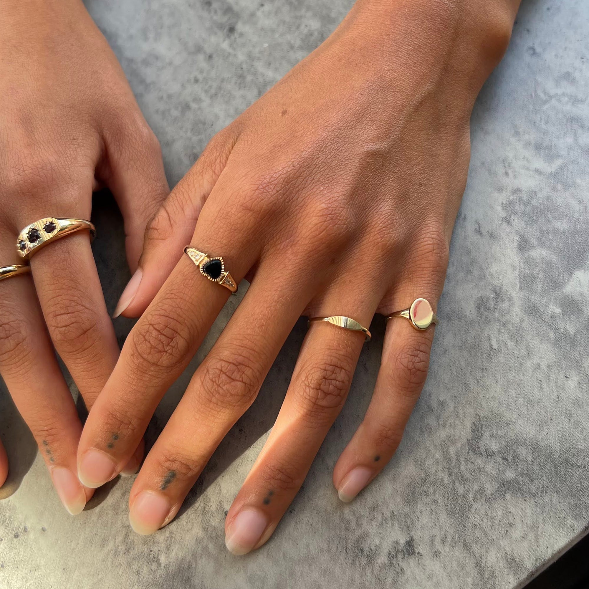 Two hands wearing gold rings with black gemstones on a gray surface - 9ct Solid Gold Oval Ring - seolgold