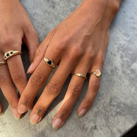 Two hands wearing gold rings with black gemstones on a gray surface - 9ct Solid Gold Oval Ring - seolgold