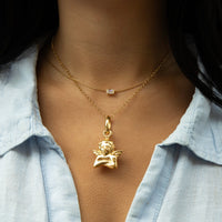 Gold necklace with an angel pendant worn by a person against a light blue shirt - seolgold