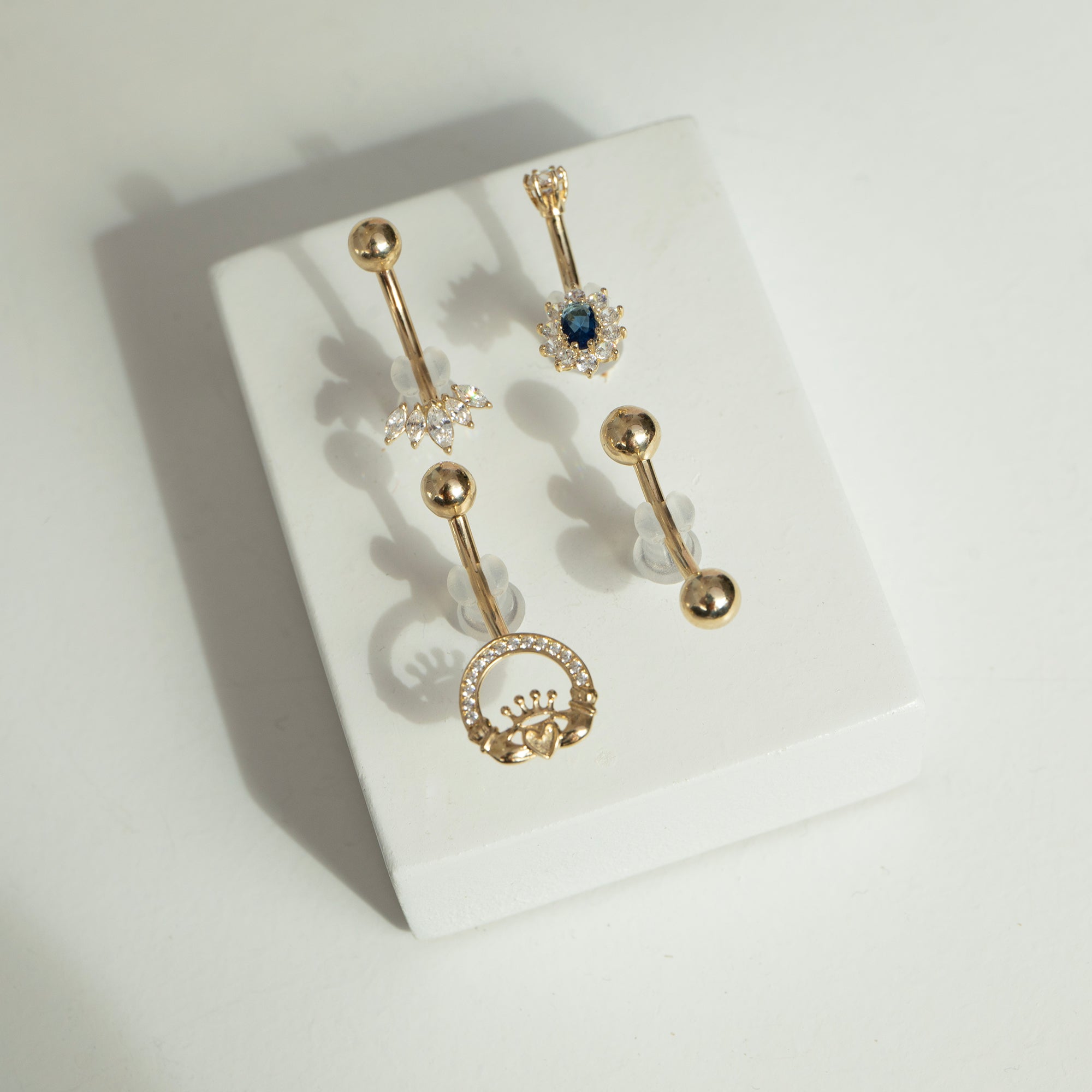 Set of gold belly buttons on a white surface - seolgold