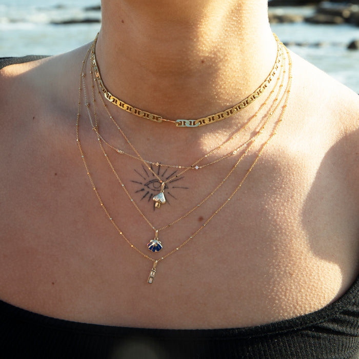 Close-up of a person wearing multiple gold necklaces with a blurred background - dianty solid gold necklace - seolgold