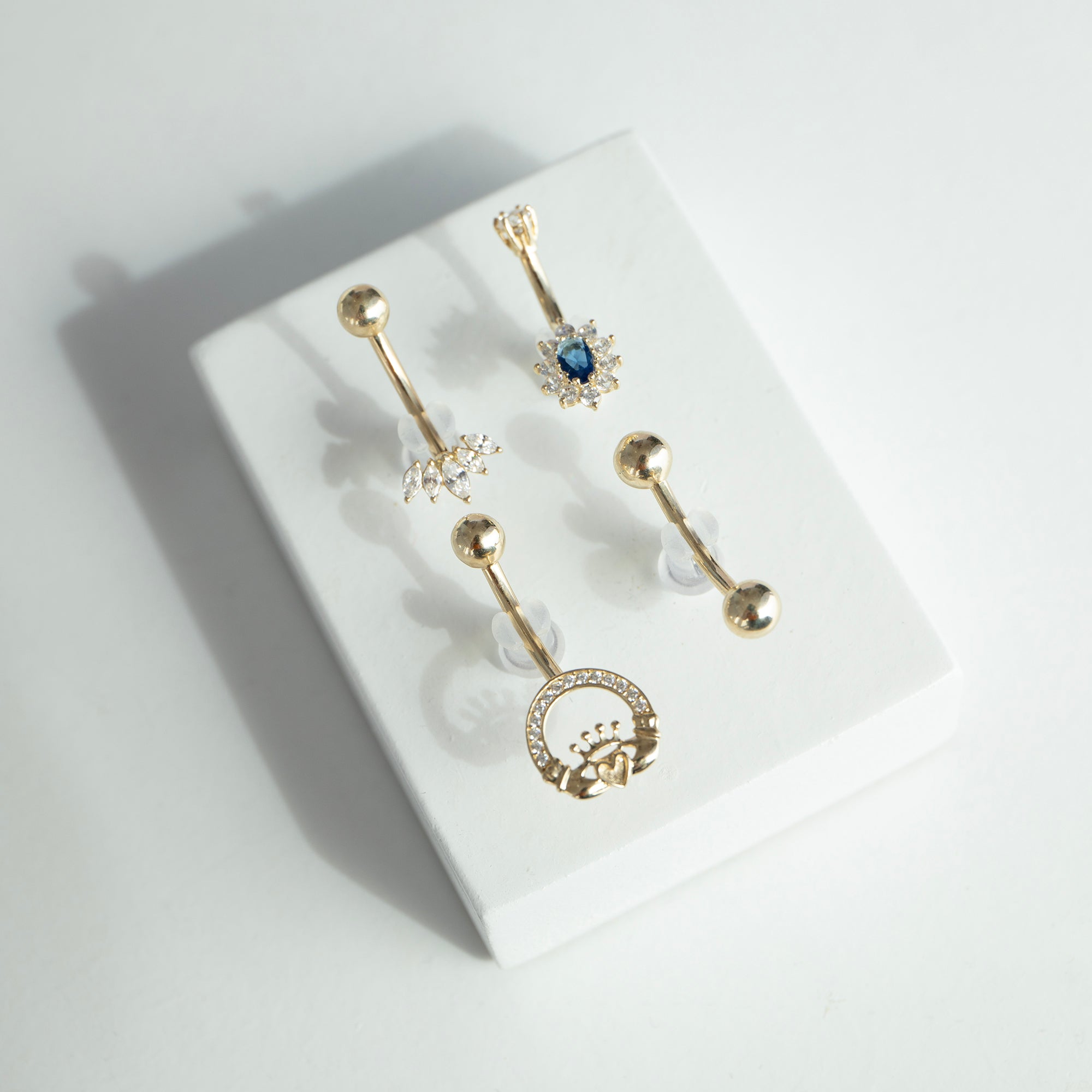 Set of 9ct gold belly buttons with decorative designs on a white surface - seolgold
