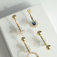 Gold belly button rings with sapphire gemstones on a white surface - seolgold
