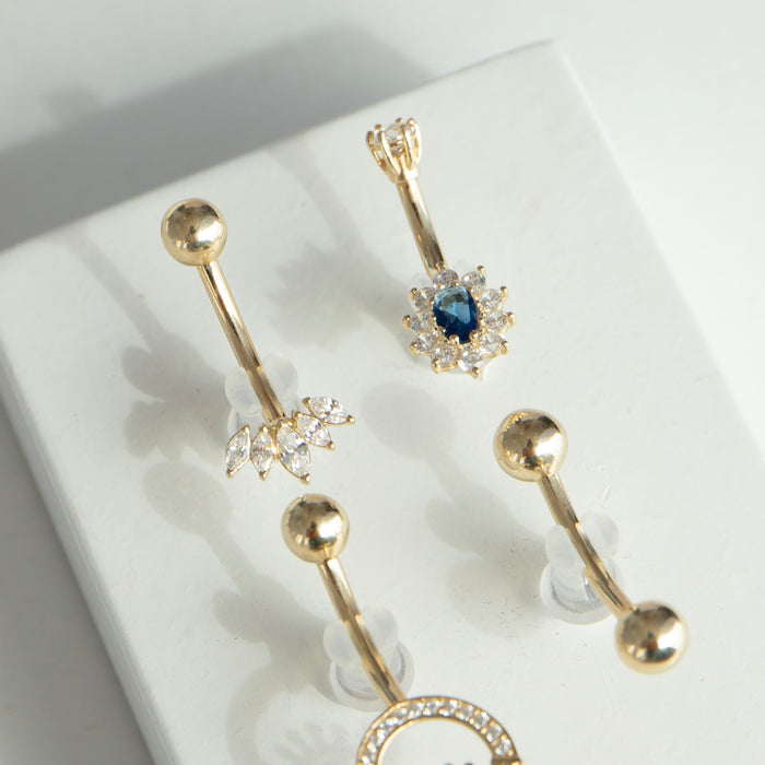 Gold belly button rings with sapphire gemstones on a white surface - seolgold