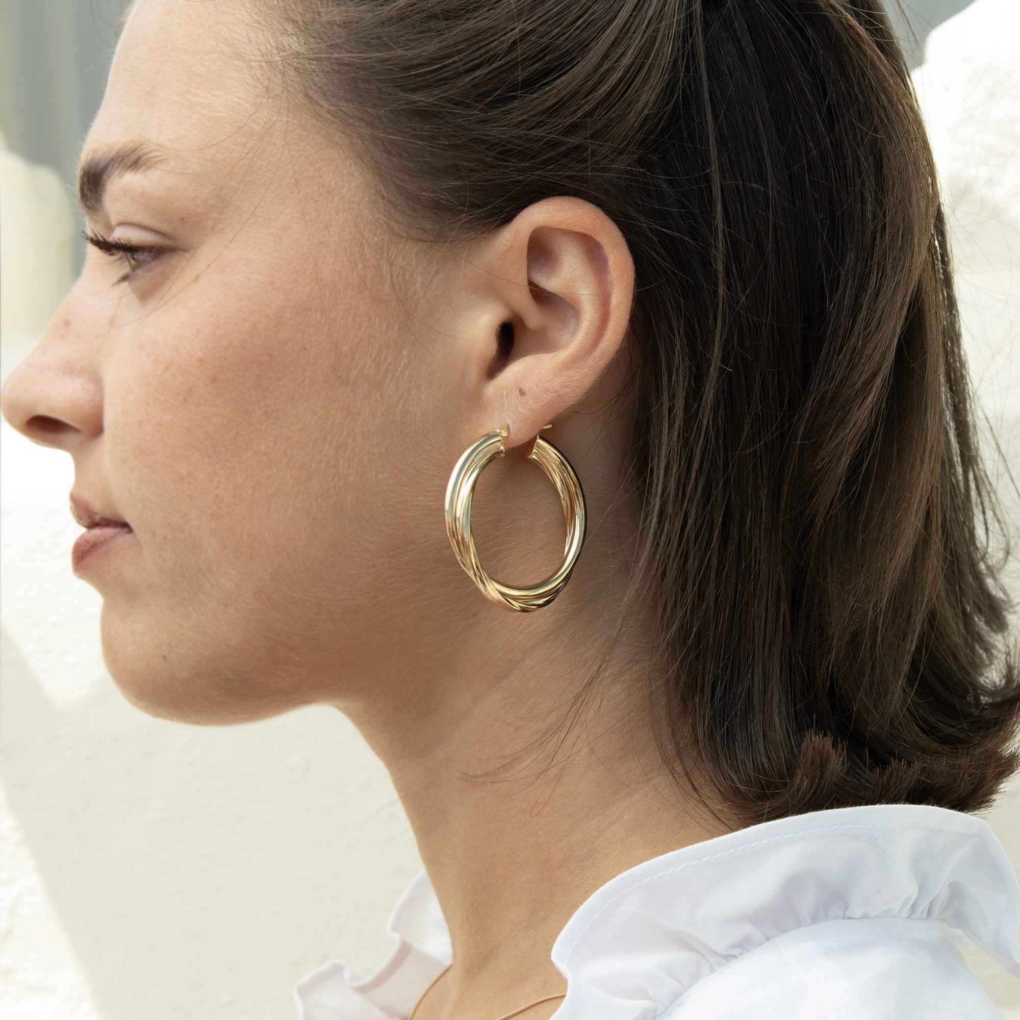 A close-up side profile of a woman wearing a thick, polished gold hoop earring - seolgold