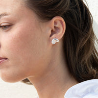 A close-up side profile of a woman wearing a small silver spiral stud earring - seolgold