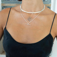 A close-up of a model's neck and chest wearing a layered silver necklace set, including a textured choker and a delicate chain with a bar pendant, styled with a black camisole top - seolgold