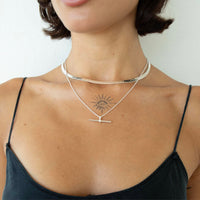 A close-up of a model's neck and upper chest wearing a layered silver necklace set. The set includes a wide, hammered band choker and a delicate chain with a T-bar pendant - seolgold