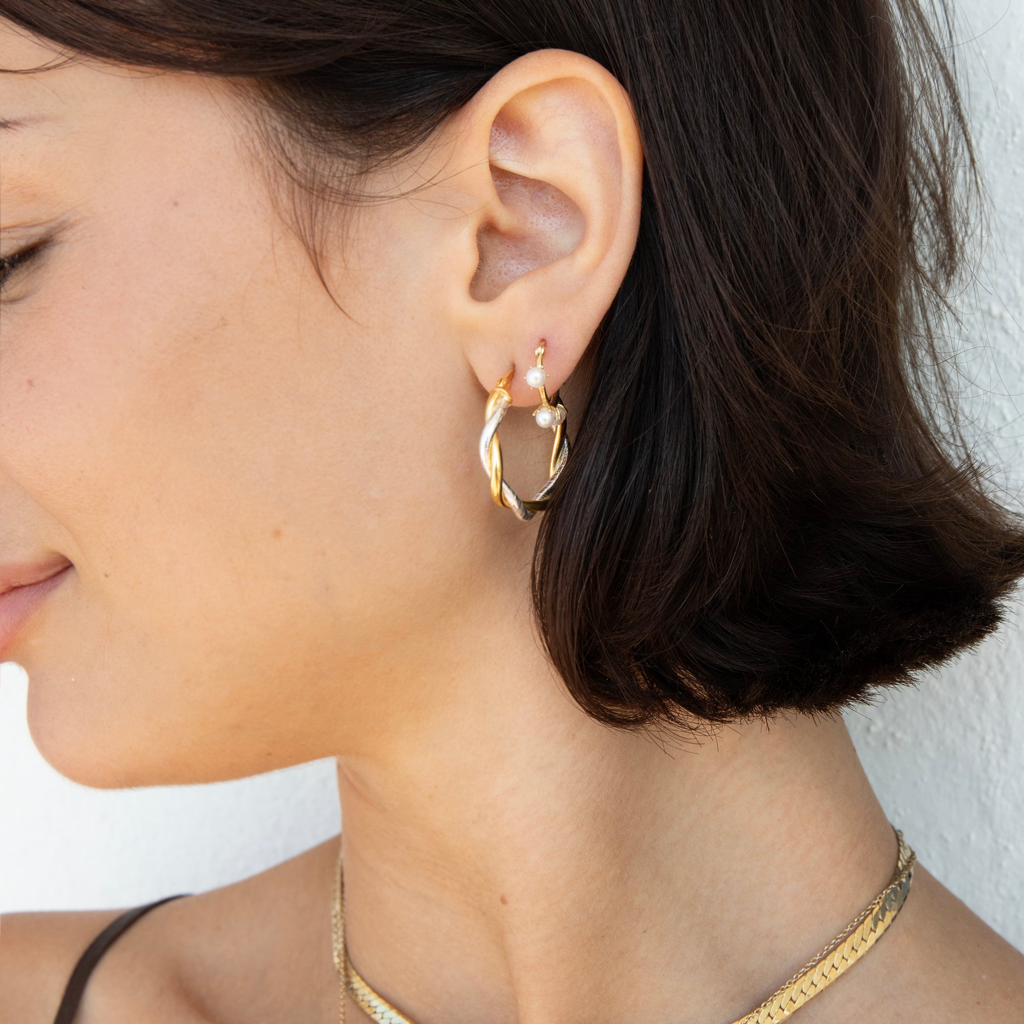 A close-up side profile of a woman wearing a delicate gold hoop earring with small pearl-like white beads at the front, along with a gold chain necklace - seolgold