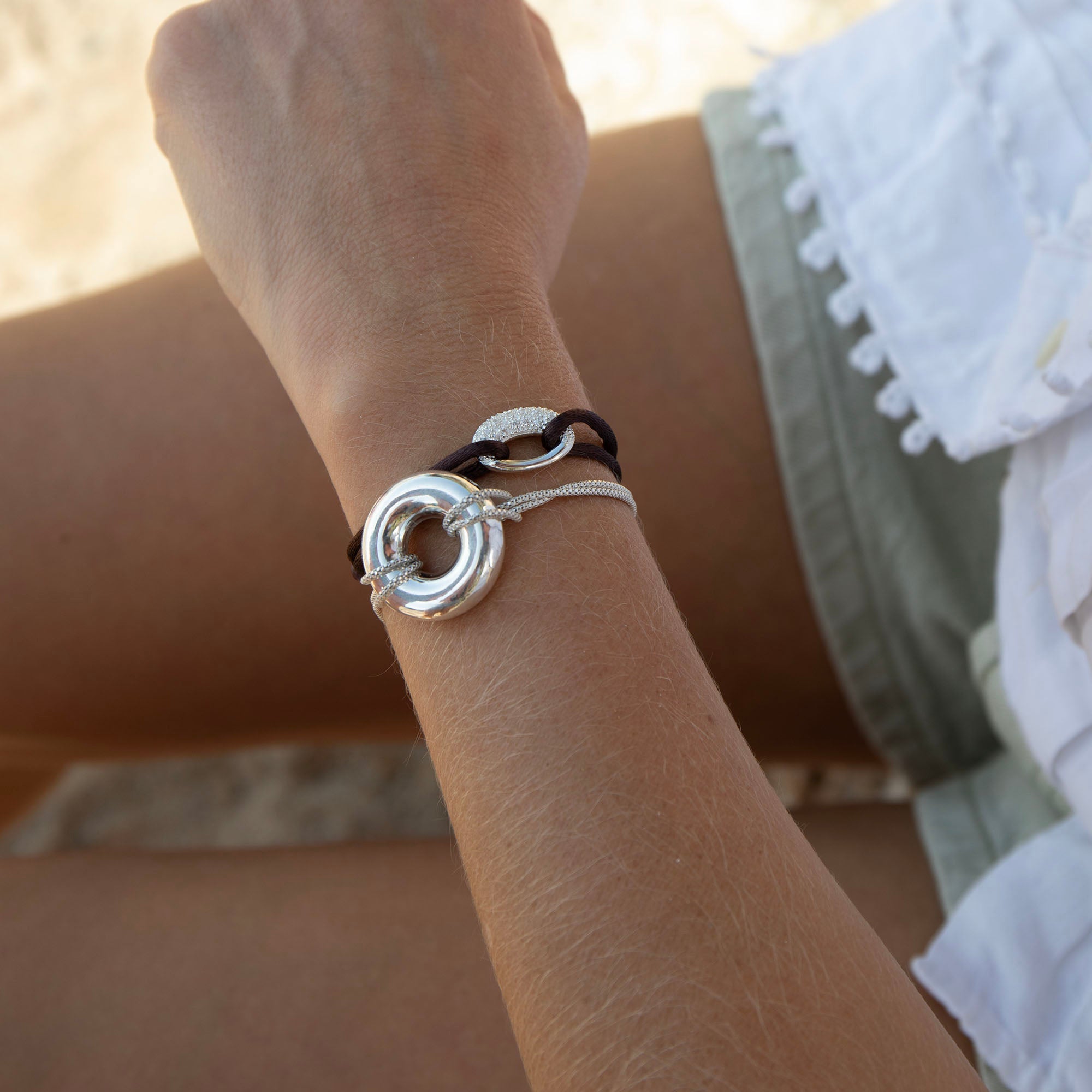 Close-up of a wrist wearing a silver bracelet with a blurred background - seolgold