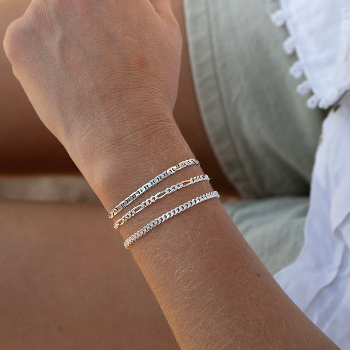 Close-up of a wrist wearing multiple silver bracelets with a blurred background - seolgold