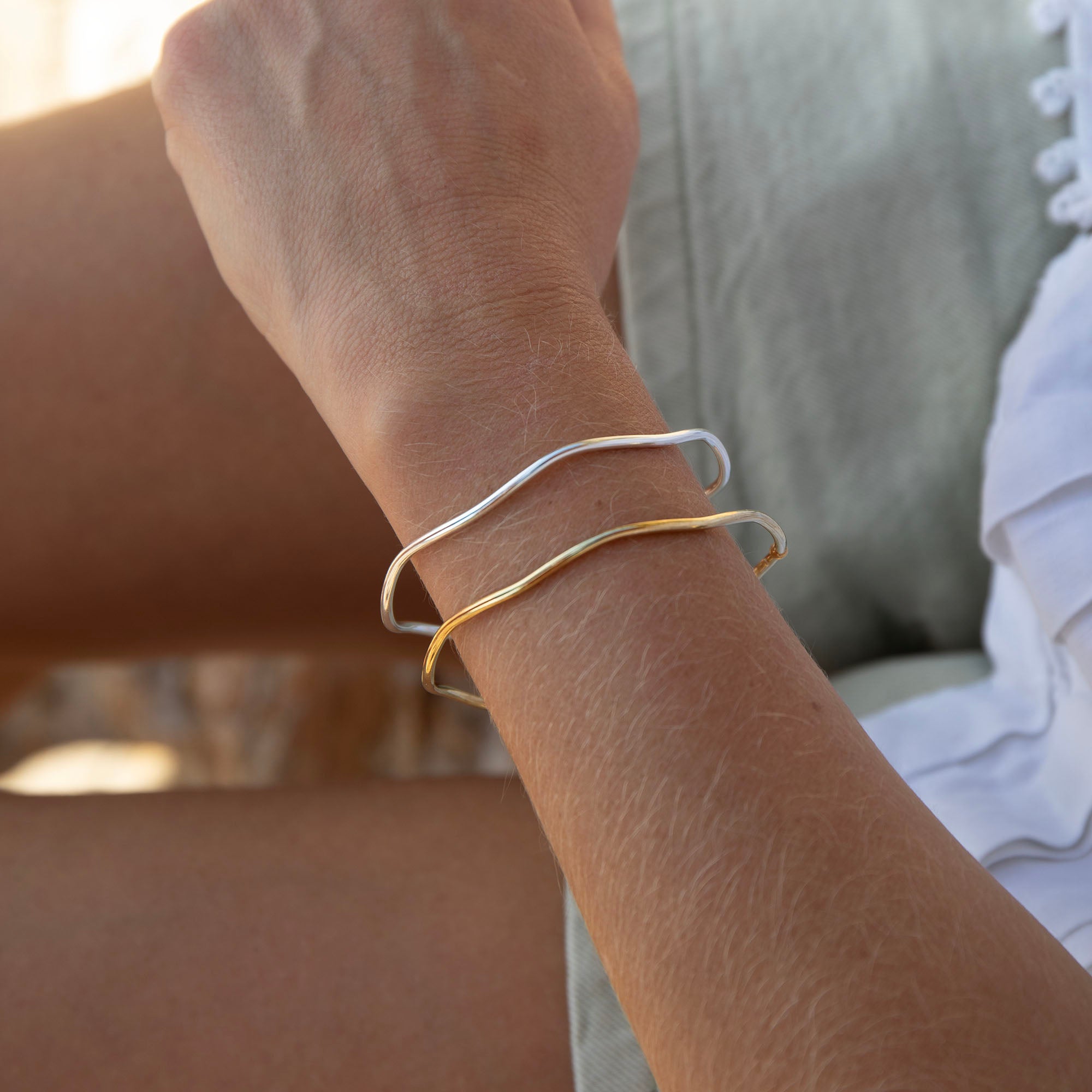 Close-up of a wrist wearing two bracelets with a blurred background - seolgold