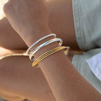 Close-up of a wrist wearing gold and silver bracelets - seolgold