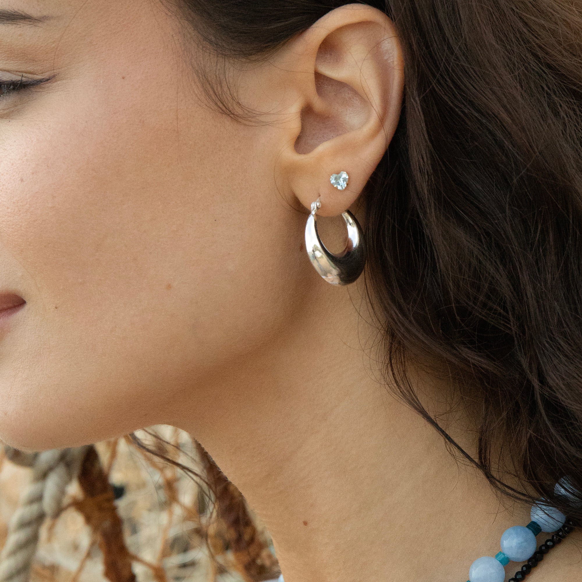 Close-up of a woman's ear wearing a silver hoop earring with a small gemstone - large chunky silver hoop - seolgold
