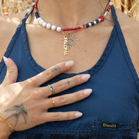 Person wearing a blue top with visible tattoos and jewelry, including a necklace and rings - seolgold