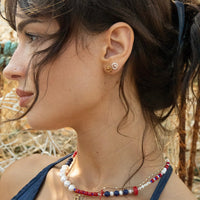 Close-up of a woman wearing earrings and a necklace with a natural background - seolgold