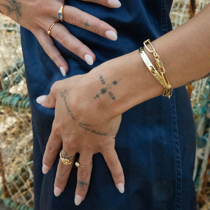 Close-up of a person's hands with tattoos and gold jewelry against a natural background - thick gold chain bracelet - seolgold