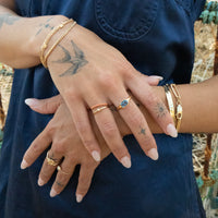 Close-up of hands with gold rings and bracelets against a blurred natural background - seolgold