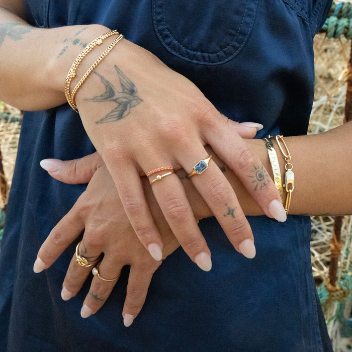 Close-up of hands with gold rings and bracelets against a blurred natural background - seolgold