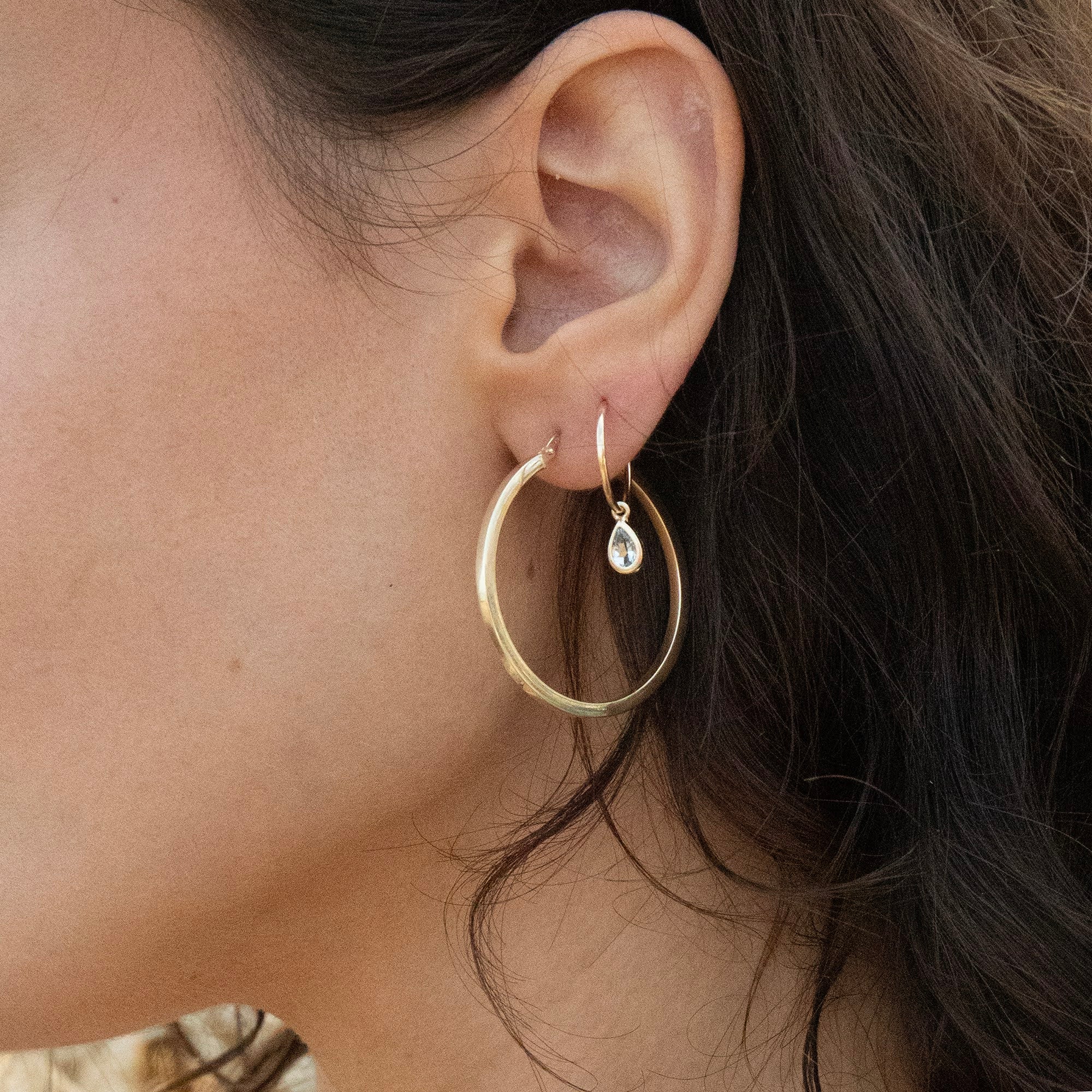 Close-up of an ear wearing gold hoop earrings with a teardrop-shaped pearl - solid gold hoops - large 9ct gold hoops - aquamarine hoops - seolgold