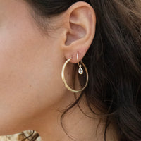 Close-up of an ear wearing gold hoop earrings with a teardrop-shaped pearl - solid gold hoops - large 9ct gold hoops - aquamarine hoops - seolgold