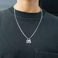 Person wearing a black shirt with a silver necklace featuring the number '95' - seolgold
