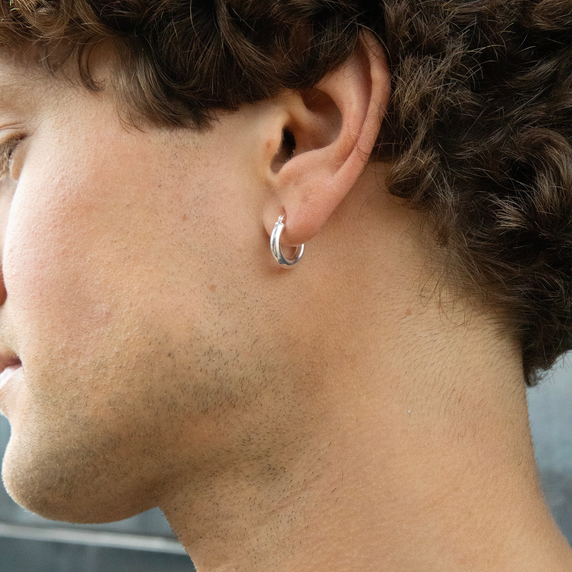 Close-up of a person wearing a silver hoop earring - seolgold