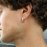 Close-up of a person wearing a silver hoop earring - seolgold