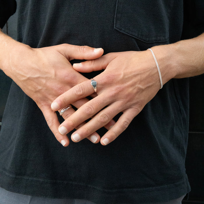 Close-up of hands with a ring and bracelet against a black background - seolgold