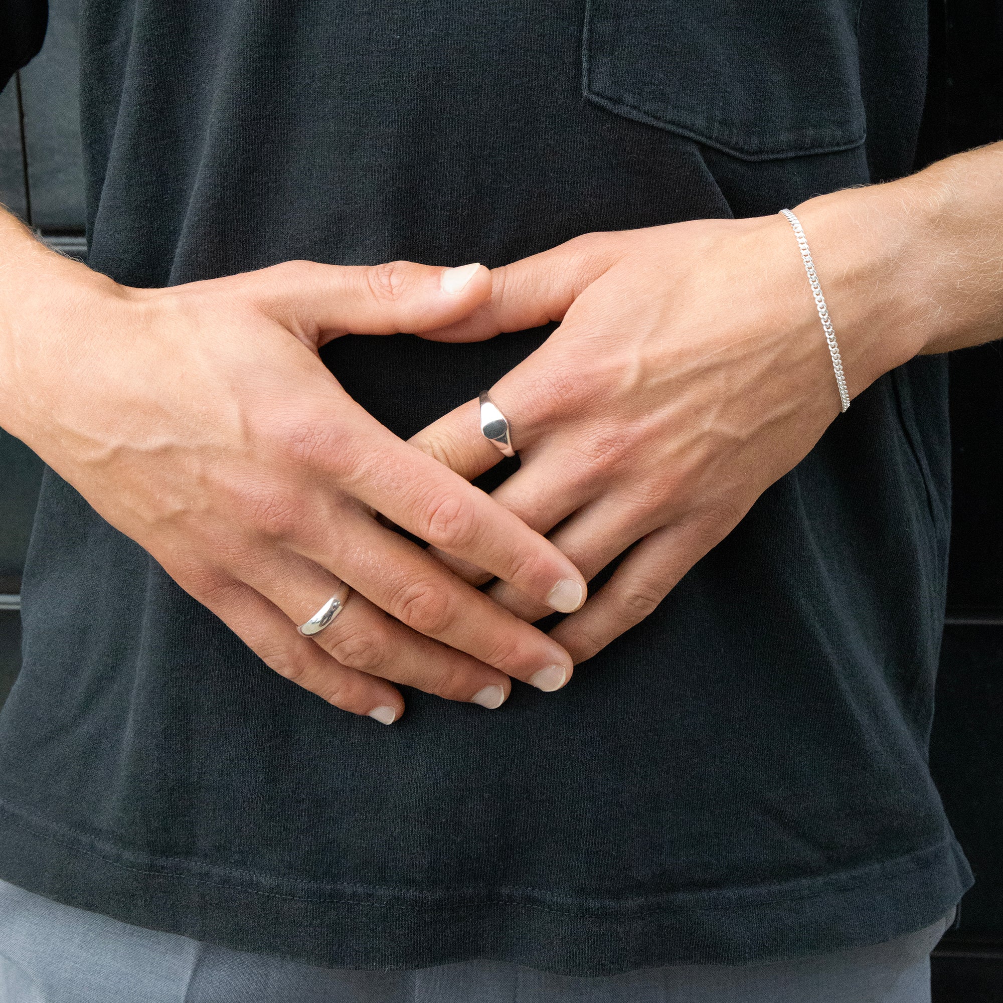 Close-up of hands with silver rings and a bracelet against a dark background - seolgold