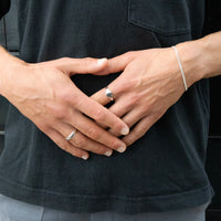 Close-up of hands with silver rings and a bracelet against a dark background - seolgold