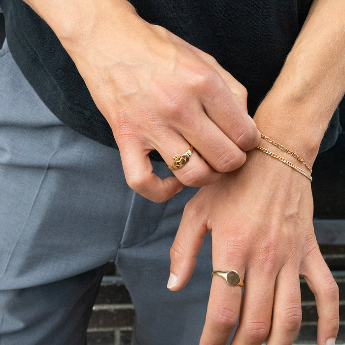Close-up of two hands with gold rings and bracelets on a neutral background - seolgold