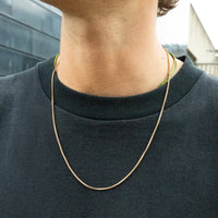 Person wearing a gold chain necklace with a blurred background - seolgold