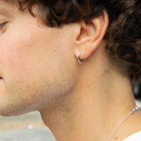 Close-up of a person wearing a silver hoop earring and necklace - seolgold