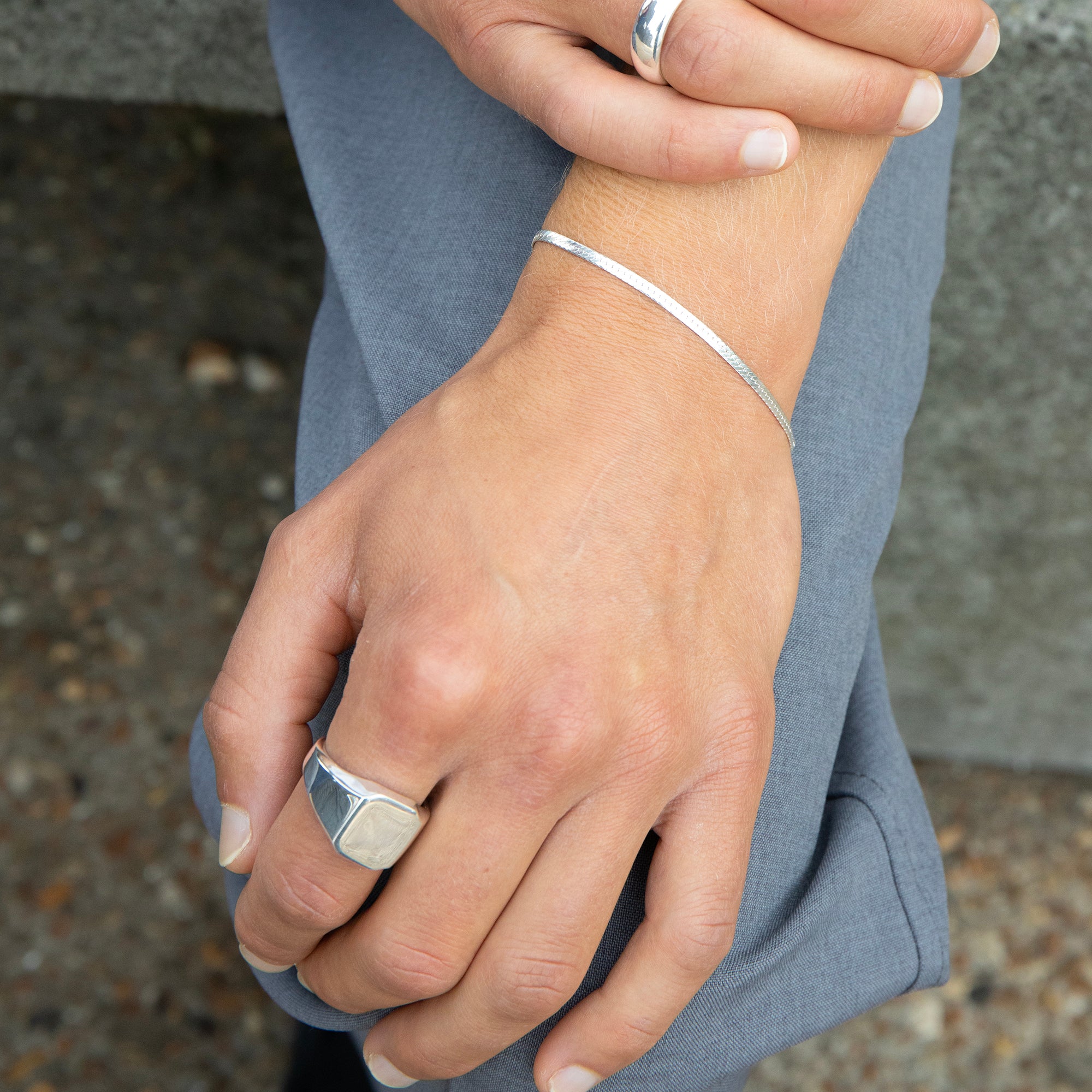 Close-up of hands wearing silver rings and bracelet with a blurred background - seolgold