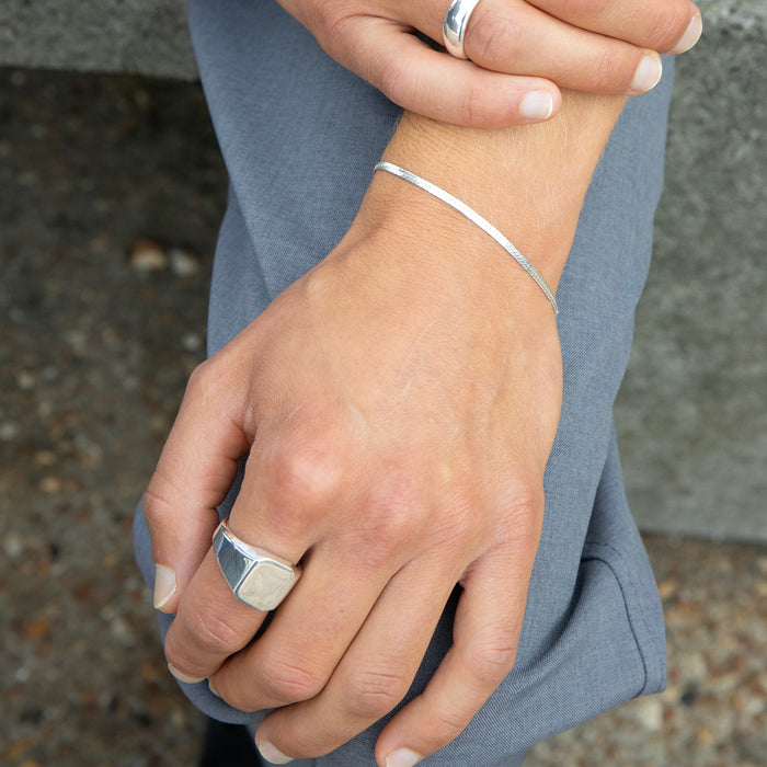Close-up of hands wearing silver rings and bracelet with a blurred background - seolgold