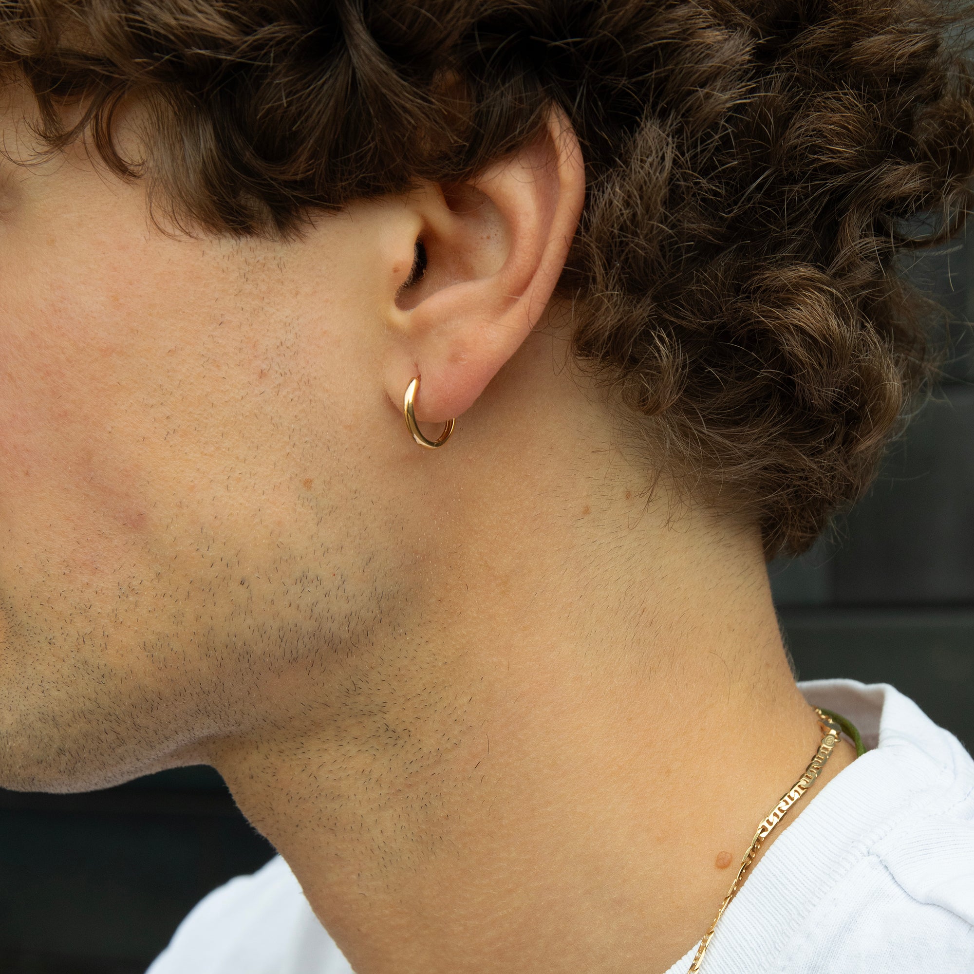 Close-up of a person wearing a gold hoop earring and necklace - seolgold