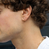 Close-up of a person wearing a gold hoop earring - seolgold