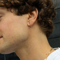 Close-up of a person wearing a gold hoop earring and necklace - seolgold