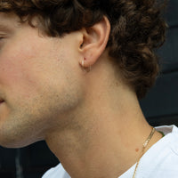 Close-up of a person wearing a gold hoop earring and necklace - seolgold