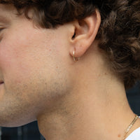 Close-up of a person wearing a gold hoop earring - seolgold