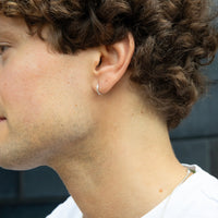 Close-up of a person wearing a silver hoop earring with a blurred background - tiny silver earring - mens silver hoop earring - seolgold